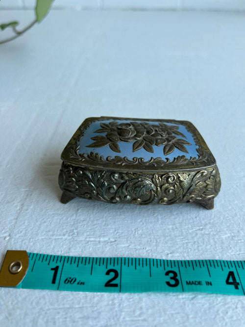 Decorative jewelry box with floral design on a white surface, measured against a ruler.