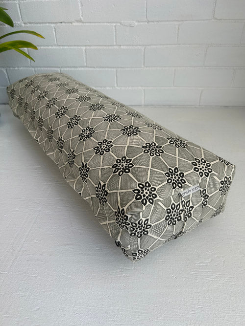 Black and cream geometric design fabric yoga bolster with floral pattern on a white surface