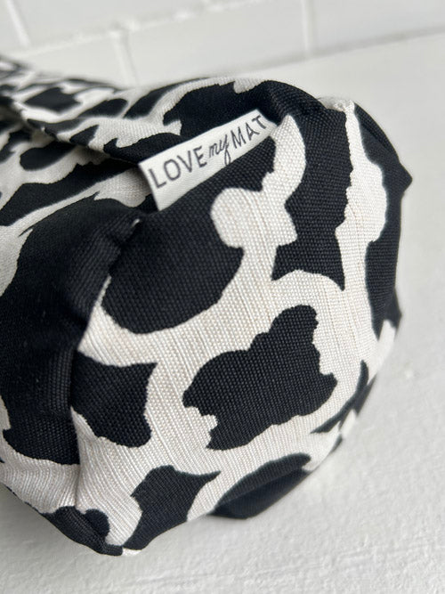 Black and white patterned small yoga bolstert with 'Love my Mat' label on a light background