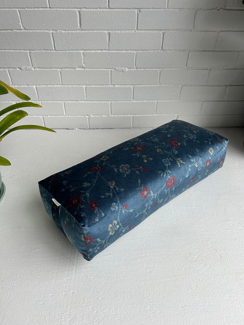 Photo of a blue floral velvet yoga bolster on an angle