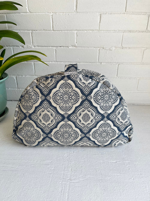 Blue and White patterned sit meditation floor cushion on a white surface and a white painted brick background