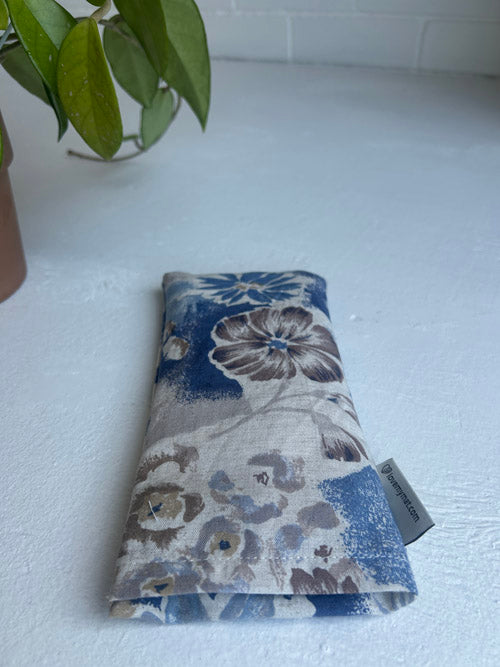 Floral-patterned fabric roll on a white surface with a plant in the background