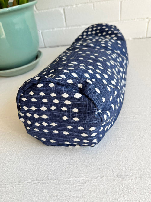 Fabric mini round yoga bolster with white diamond patterns shown on a white surface, and white background.