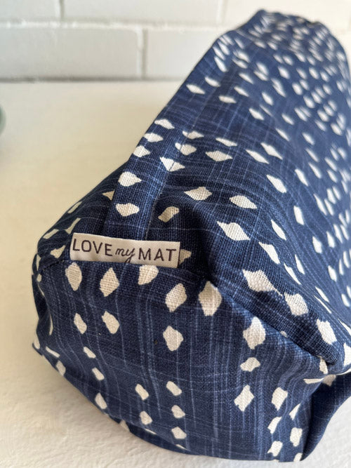 Close up of blue and white diamond patterned min round yoga bolster with a label that say "LOVE my MAT".