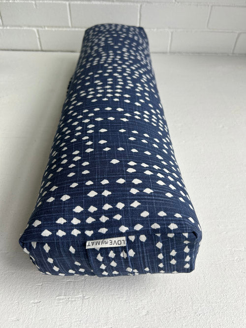 Blue and white patterned yoga bolster with a visible brand label on a white surface.