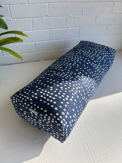 Blue and white yoga bolster laying on a white surface with a white background