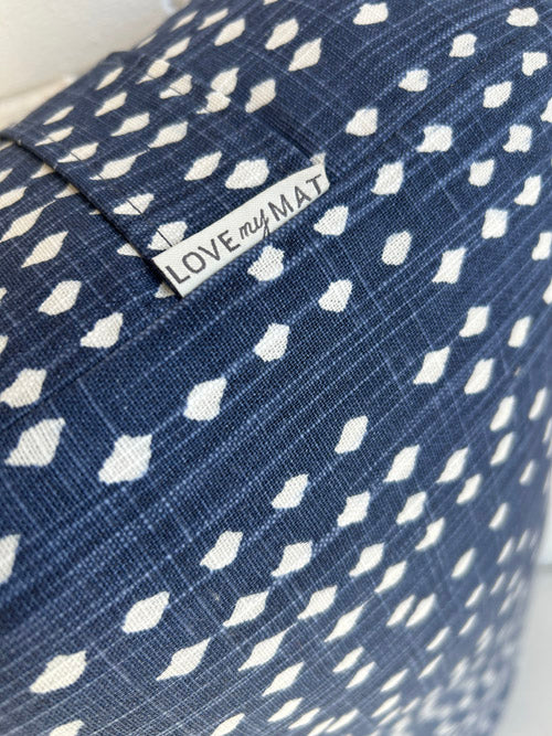 close up of fabric yoga bolster with blue background and small white diamond print with a label that says 'LOVE my MAT'.