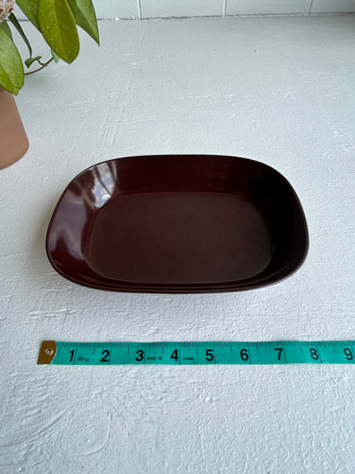 Brown rectangular plate on a white surface with a measuring tape for scale.