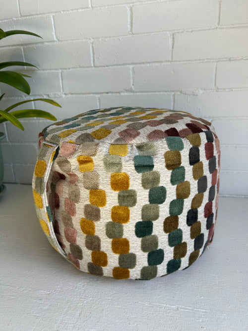 Multicolored patterned Meditation Cushion on a white surface with a white brick wall background