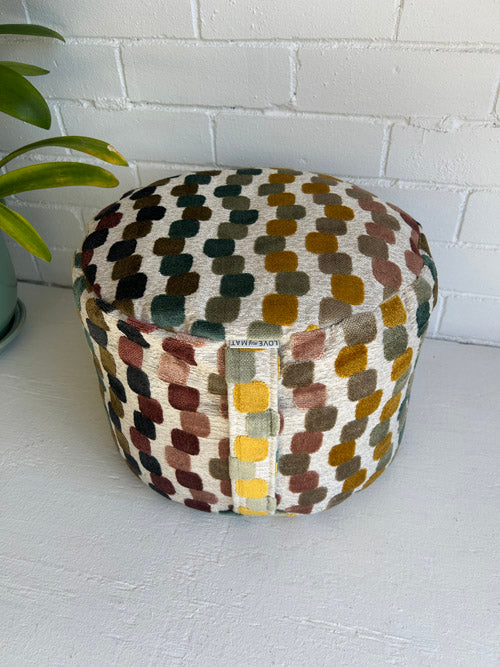 Colourful Patterned meditation Cushion on a white surface with a plant in the background