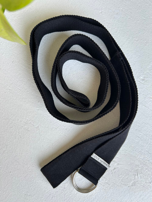 Black belt with a metal buckle on a light gray background