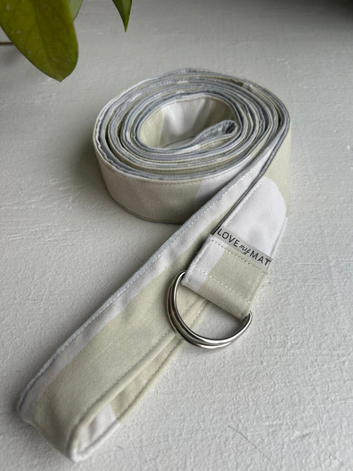 Yoga strap with a metal ring on a light gray surface