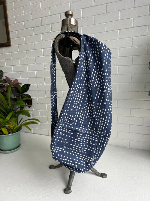 Navy blue fabric with white patterns draped over a mannequin against a white brick wall.