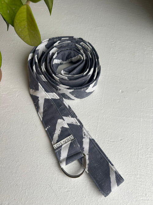 Yoga strap with gray and white pattern on a light gray surface