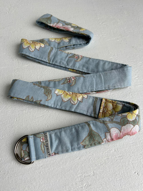 Blue floral patterned yoga strap arranged in a zigzag pattern on a white background