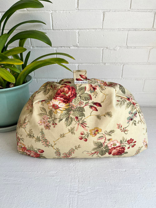 Floral-patterned fabric meditation cushion on a white surface with a plant in the background
