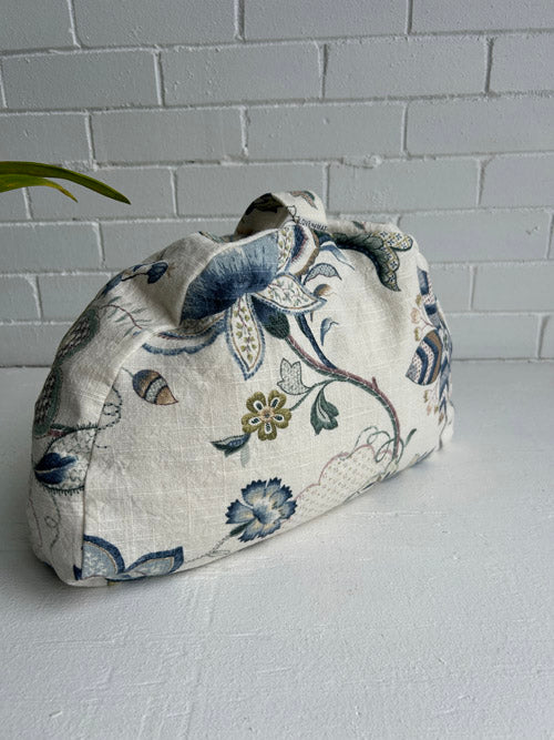 Floral-patterned fabric meditation cushion on a white surface with a white tiled wall background