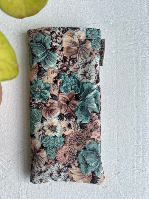 Floral patterned eye pillow on a textured white surface