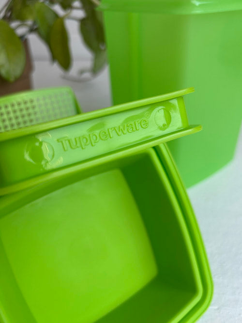 Green Tupperware container with a lid on a white surface.