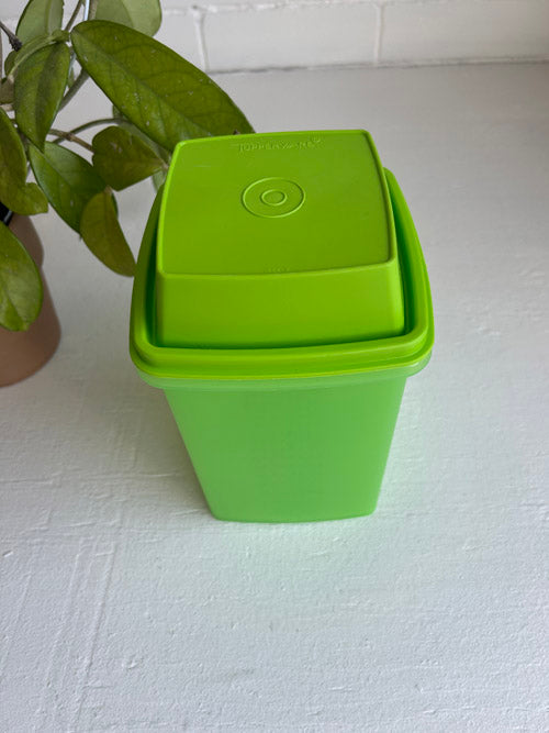 Green Tupperware plastic container with a lid on a white surface