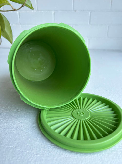 Green silicone lid on a white surface with a white brick wall background