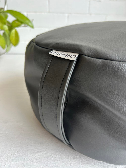 Gray leather bag with a visible brand label on a white surface.