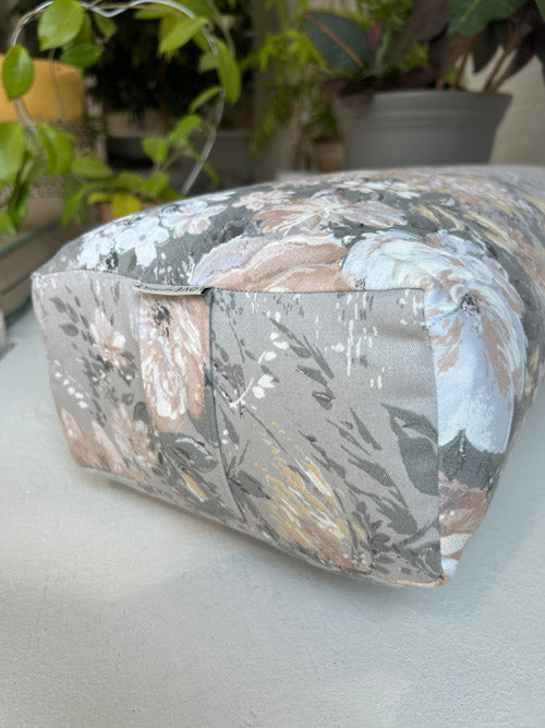 Floral-patterned Canadian made long yoga boslter on a light surface with plants in the background