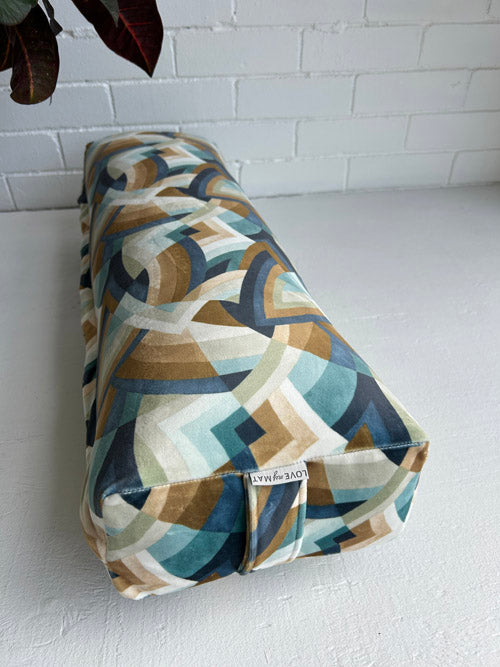 Patterned yoga bolster on a white surface with a white brick wall background