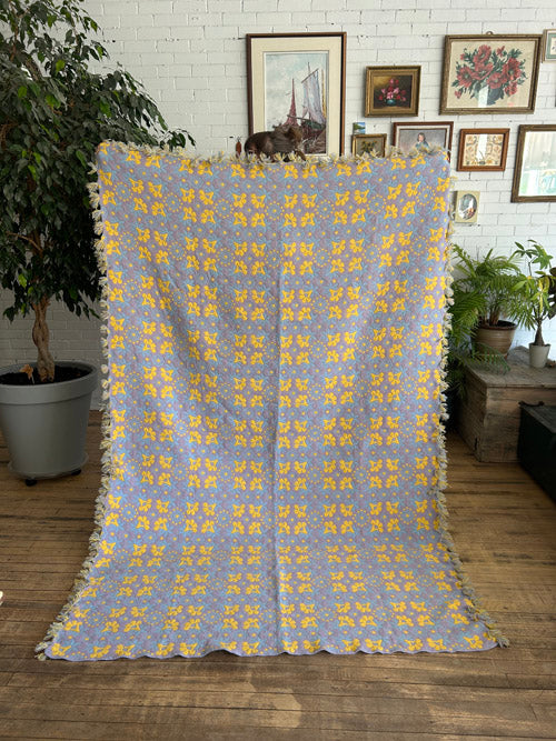 Floral patterned blanket draped over a chair in a room with framed pictures on the wall.