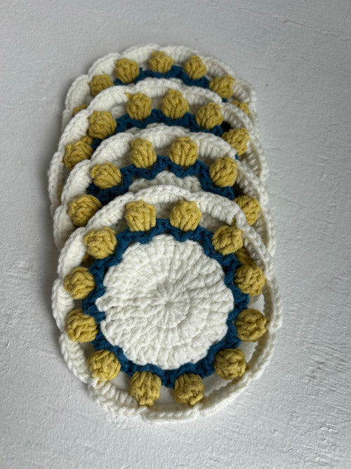 Set of crocheted coasters with blue and yellow pattern on a gray background