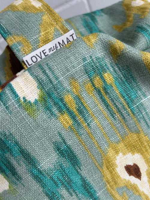 Close-up of a fabric meditation cushion with a 'LOVE my MAT' label on a blurred background
