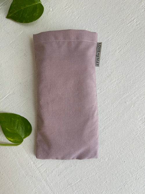 Purple fabric eye pillow with a tag on a white background