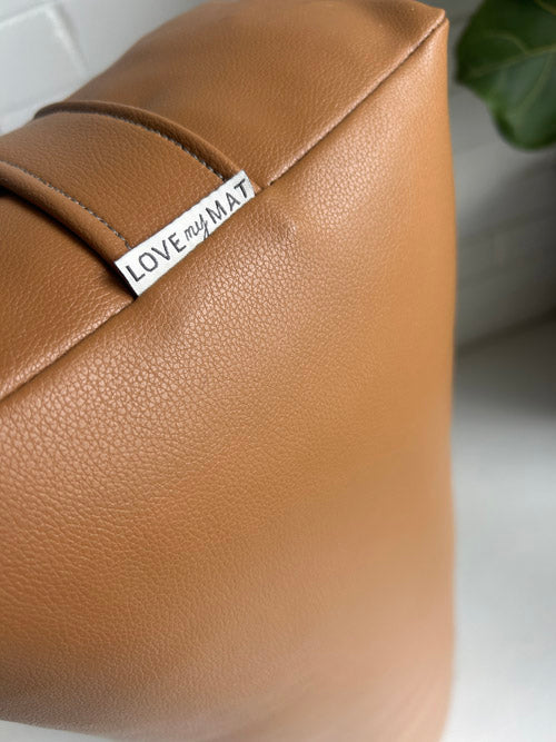 Brown  vinyl yoga bolster with 'LOVE my MAT' label on a white background