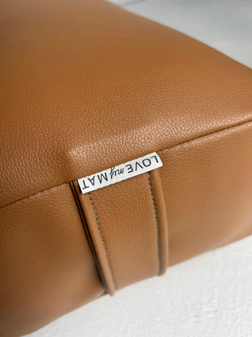 Brown vinyl yoga bolster with 'LOVE my MAT' label on a white background