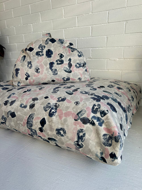 Modern brush stroke print bedding set on a bed against a white brick wall.