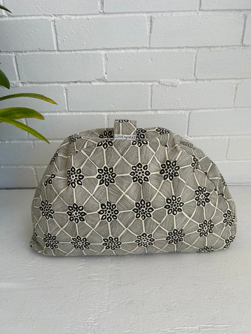 Patterned fabric meditation cushion on a white surface with a white brick wall background