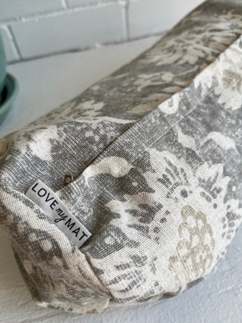 Close up of Fabric min round yoga bolster with 'LOVE my MAT' label on a light background