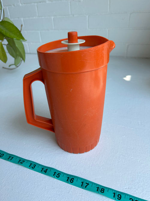 Orange Tupperware juice pitcher on white background