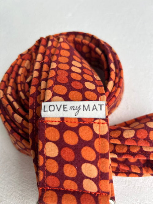 Orange and deep red patterned yoga  strap with 'LOVE my MAT' label on a white background
