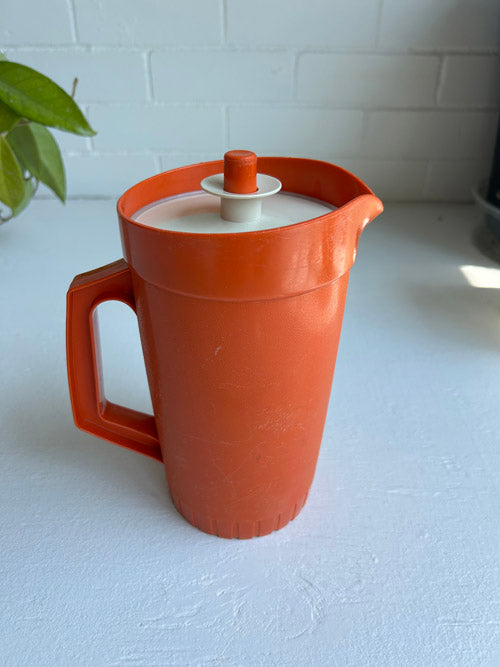 Orange pitcher with a white interior on a light surface.