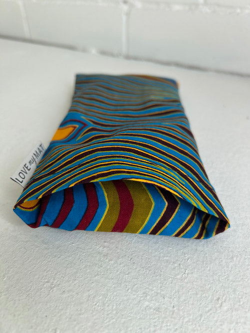 Fabric eye pillow with colorful stripes on a white surface