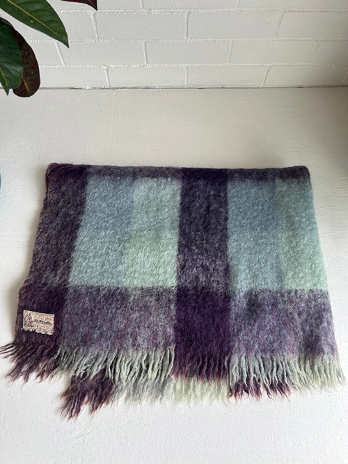 Plaid blanket with fringes on a white surface