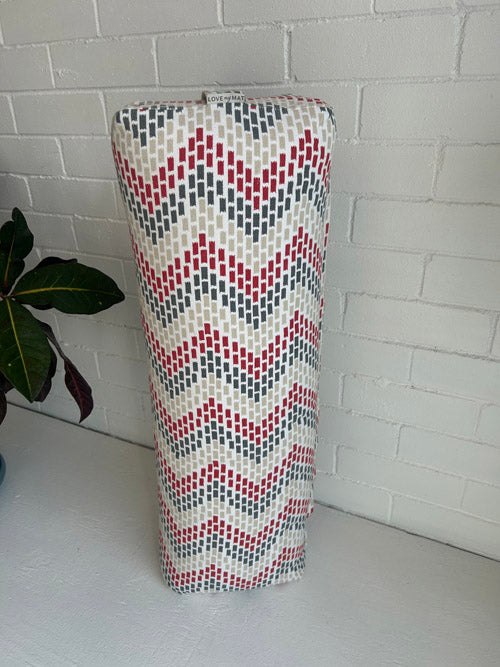 Tall yoga bolster with a geometric pattern on a white tiled floor.