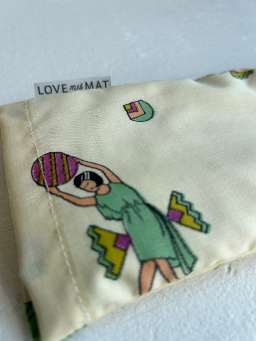 Eye Pillow with colourful design of a woman holding a heart, on a beige background.