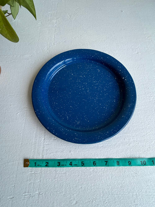 Blue speckled plate on a white surface with a measuring tape for scale.