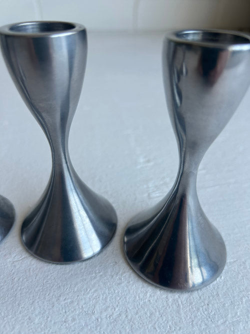 Two metallic candle holders on a white surface