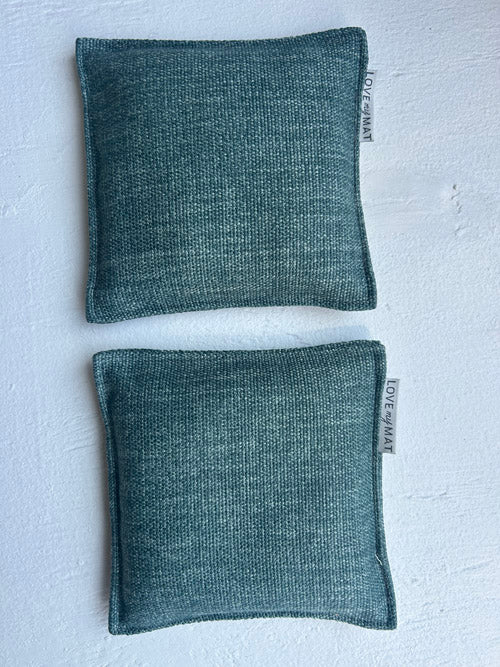 Two green fabric pouches on a light gray background