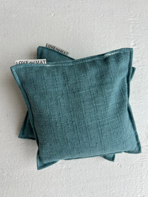 Two teal yoga knee pillows on a white background