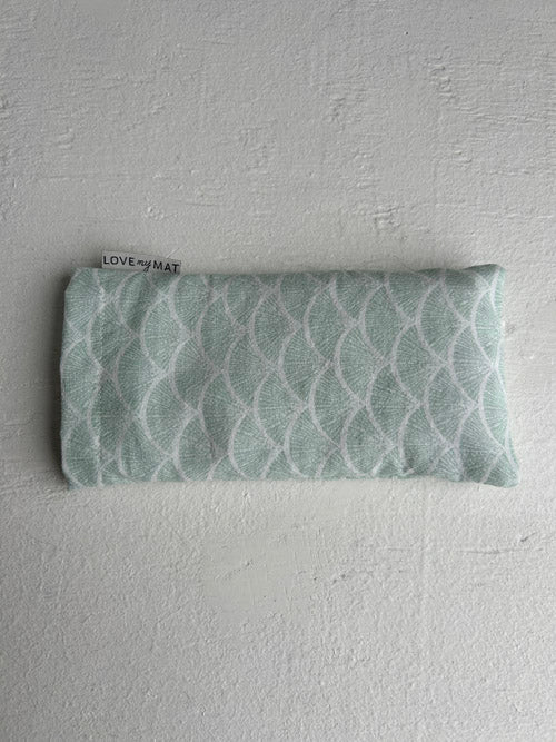 Folded fabric eye pillow with a pattern on a white background