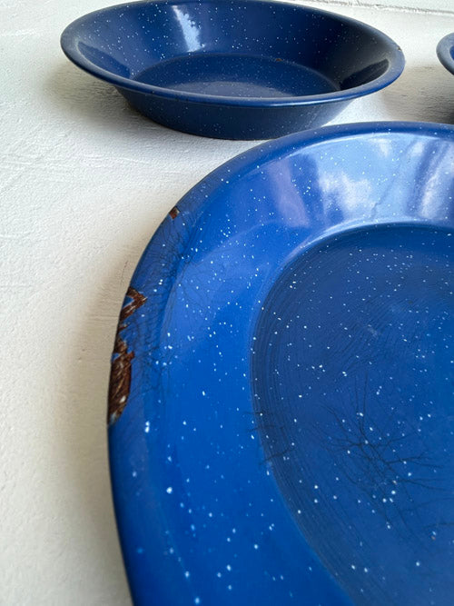 Three blue ceramic plates with white speckled pattern on a blue surface